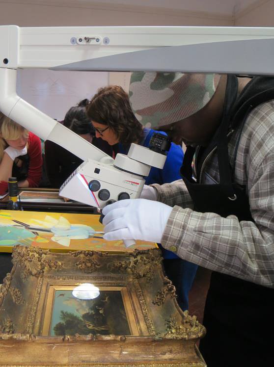 Click the image for a view of: Barnabas using the stereo microscope to examine a Bailey painting